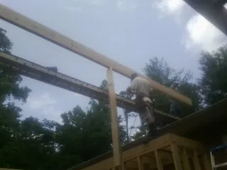 Carpenter setting a ridge beam over a new addition frame — Ice Dam Removal by Roofing Brothers in Islandton