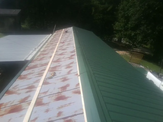 Old rusted panels beside newly installed green metal roofing — Wind Damage Roof Repair by Roofing Brothers in Islandton
