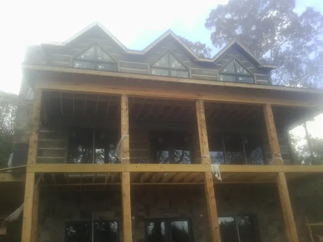 Dormers and porch framing on a large log home under construction — Roof Coating work by our crew in Islandton