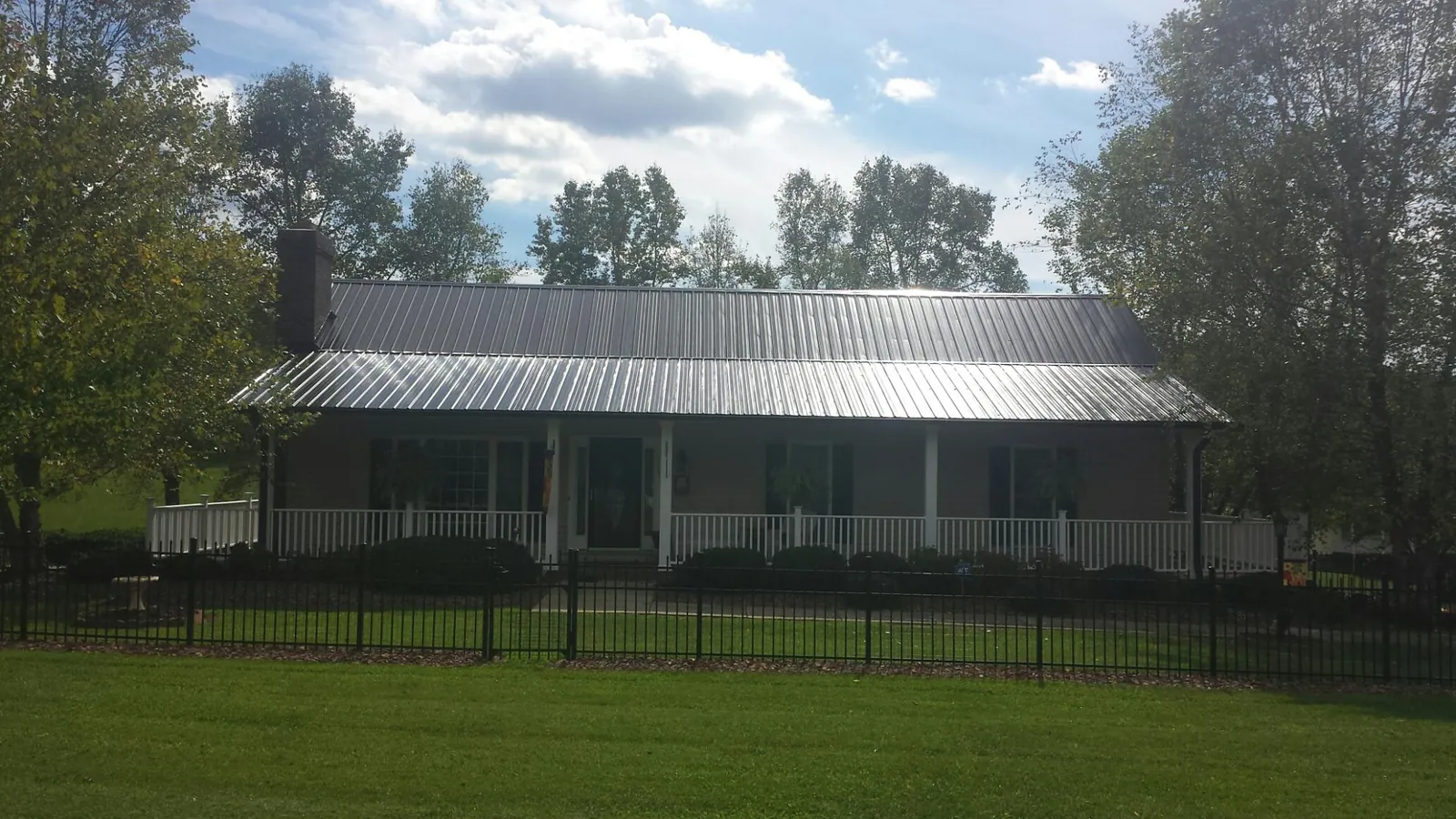 Gray metal roof on a brick ranch with a full width front porch — Gutter Guard Installation work by our crew in Islandton