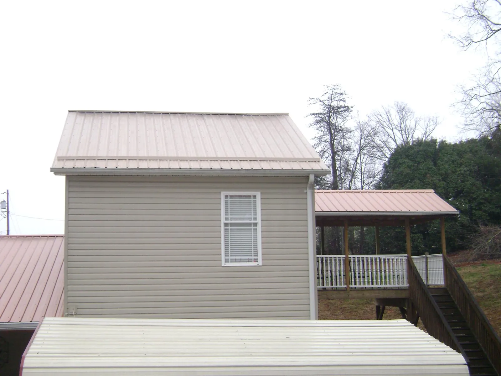 Tan metal roofs on a two story addition and attached porch, from a Roof Replacement job in Islandton