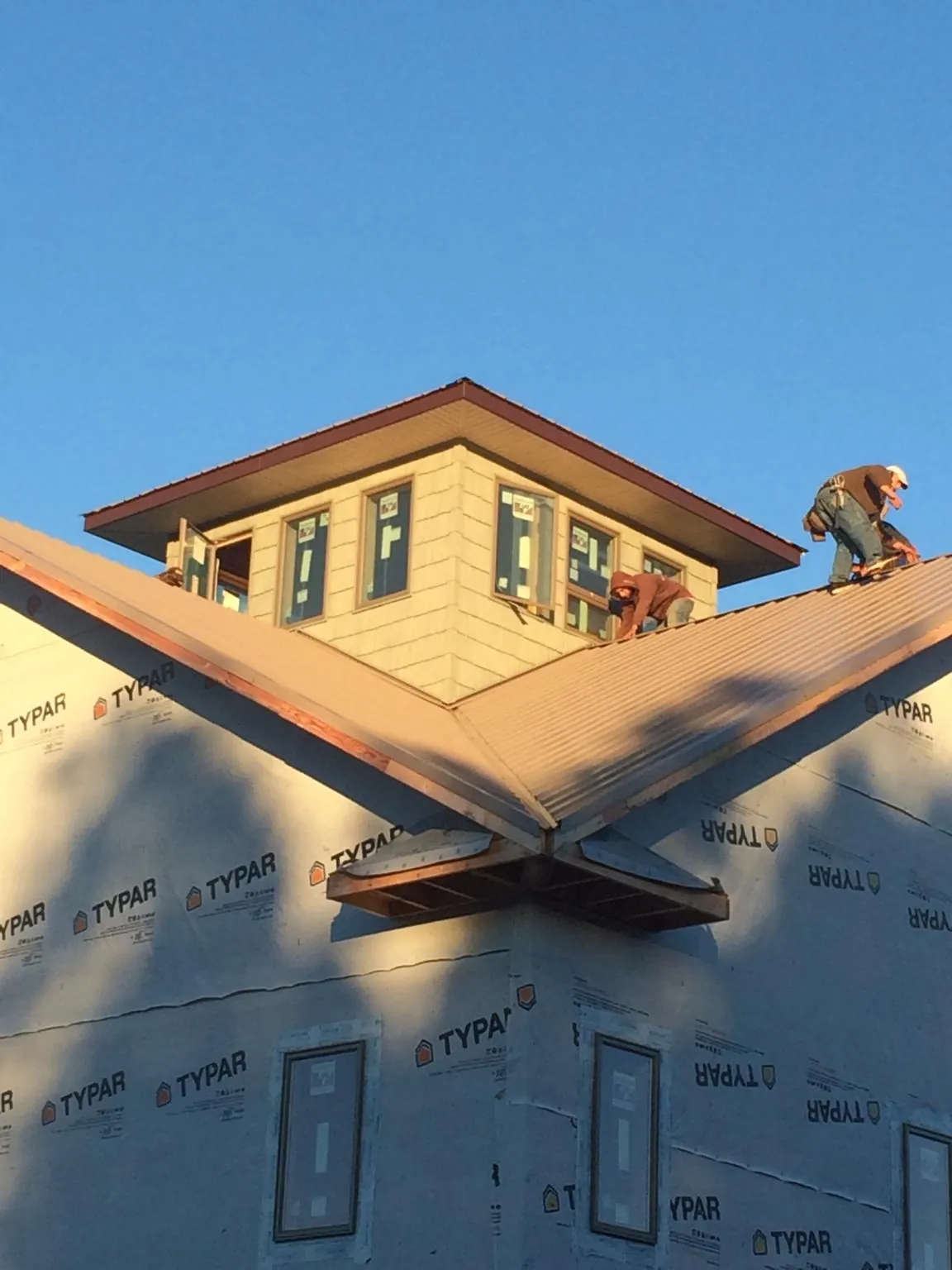 Roofers working around a rooftop cupola on a new metal roof at sunset — Roof Waterproofing in Islandton by Roofing Brothers